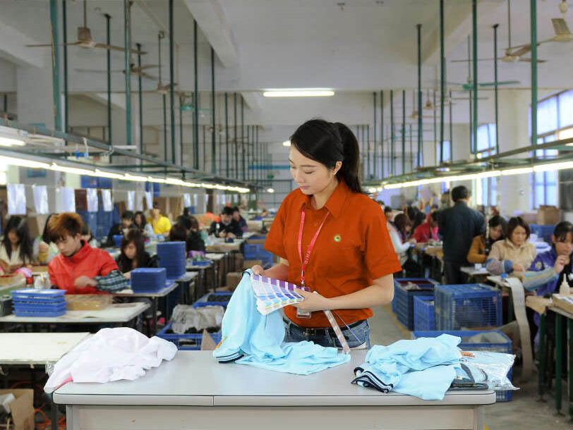 An image depicting the Jinfeng Apparel production team meticulously working on garment details, emphasizing the importance of each step in the manufacturing process. The image highlights our commitment to quality and precision, even when preparing for expedited orders for strategic partners.n garments