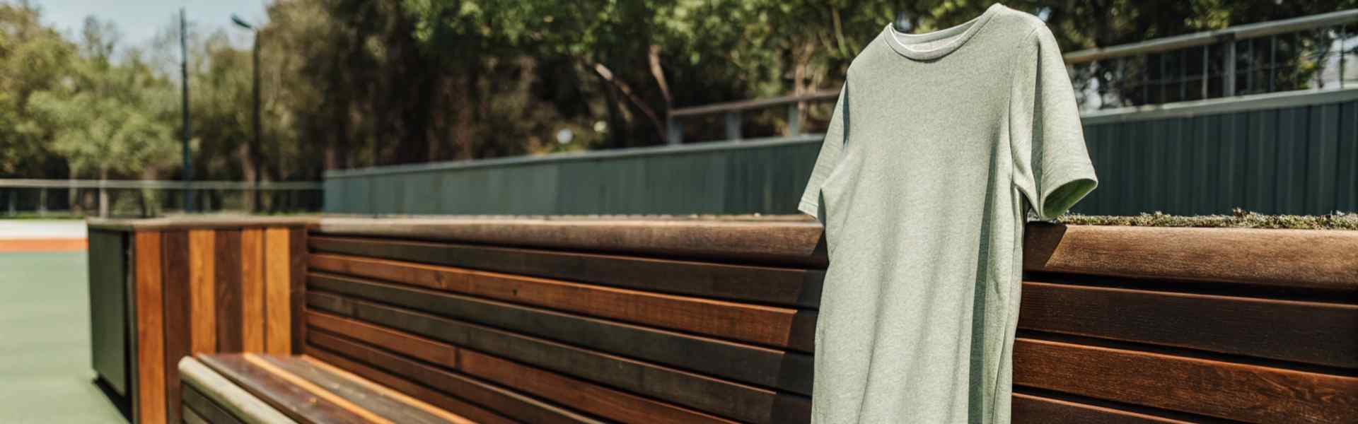 Light green dress, denim jacket, and white sneakers placed on a wooden bench.