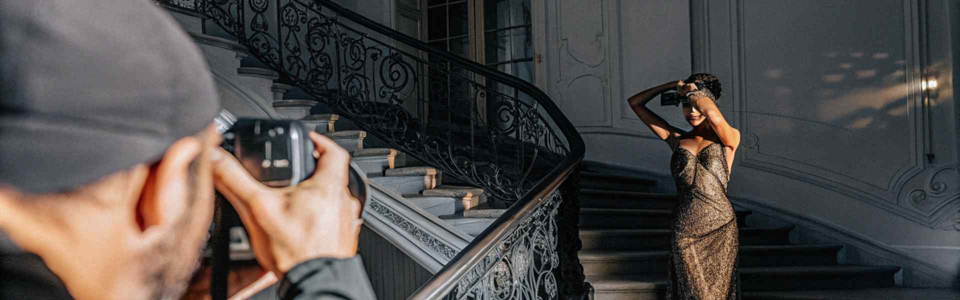 Photographer capturing a woman in a shimmering gown on a grand staircase.