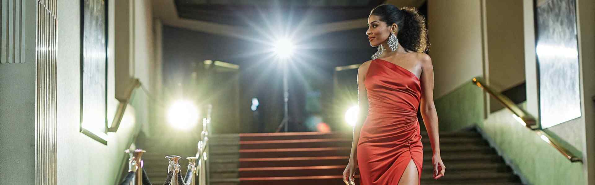 Woman in a red dress walking confidently on the red carpet.