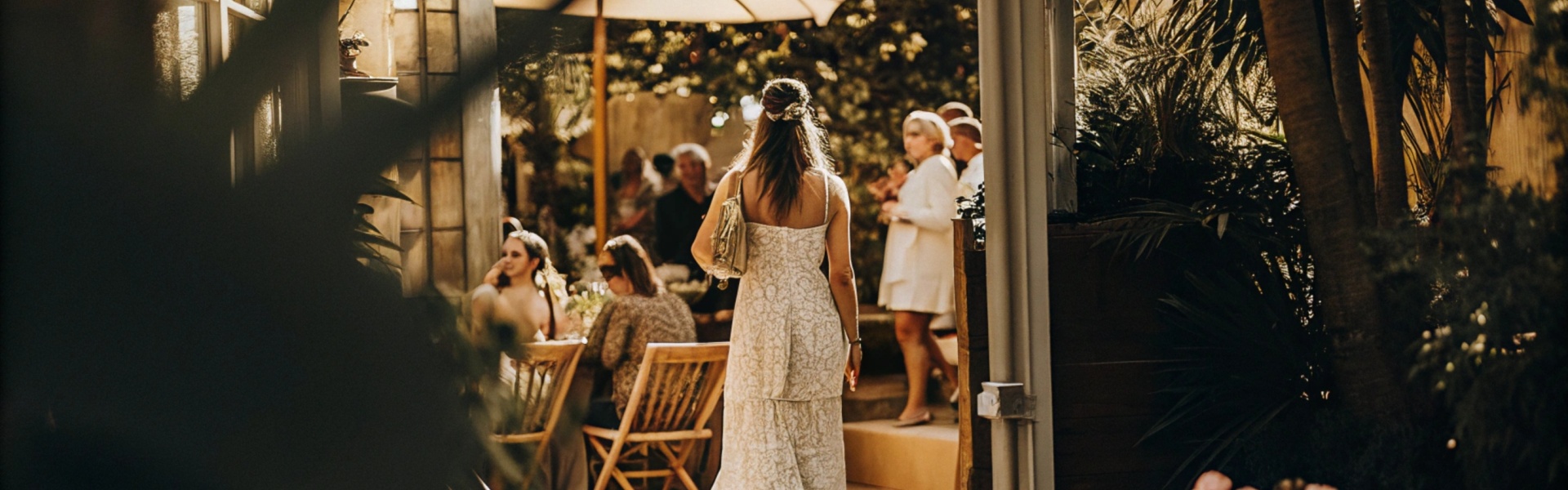 Woman in a white lace dress walking into a garden party.