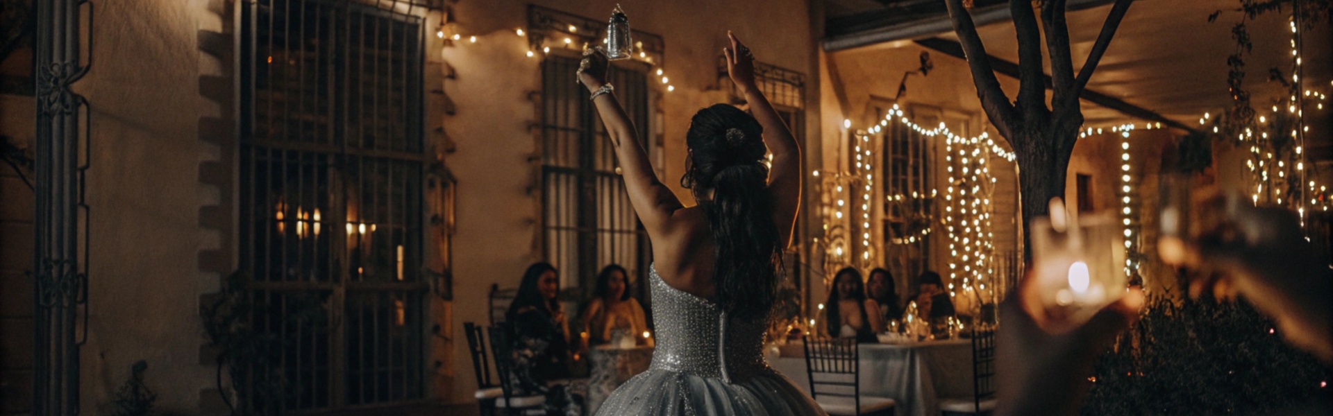 Woman in a sparkling gown celebrating at a garden party with string lights.