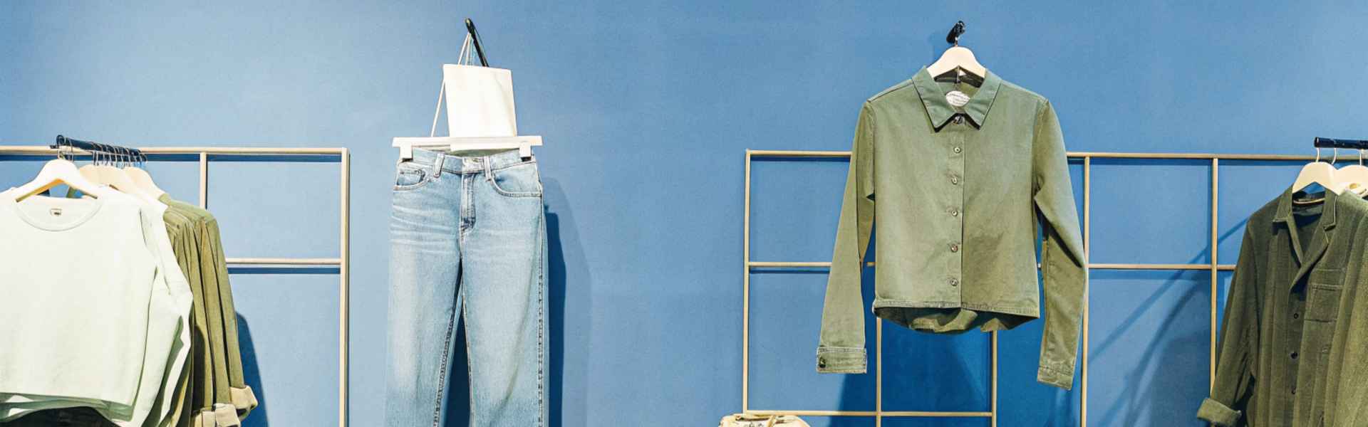 Display of green and blue casual clothing with accessories against a blue backdrop.