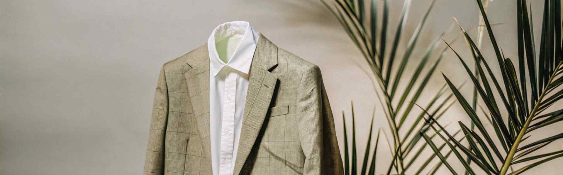 A beige blazer and white shirt paired with black leather shoes, styled against greenery.