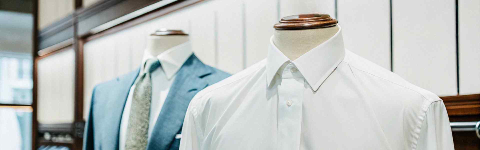 Mannequins showcasing white shirt and blue suit with tie.