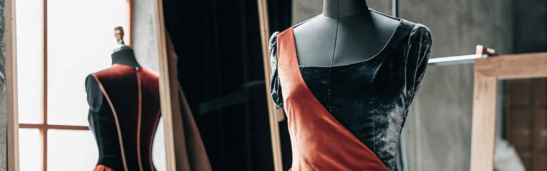 Black and red velvet gown on a mannequin in a designer studio.