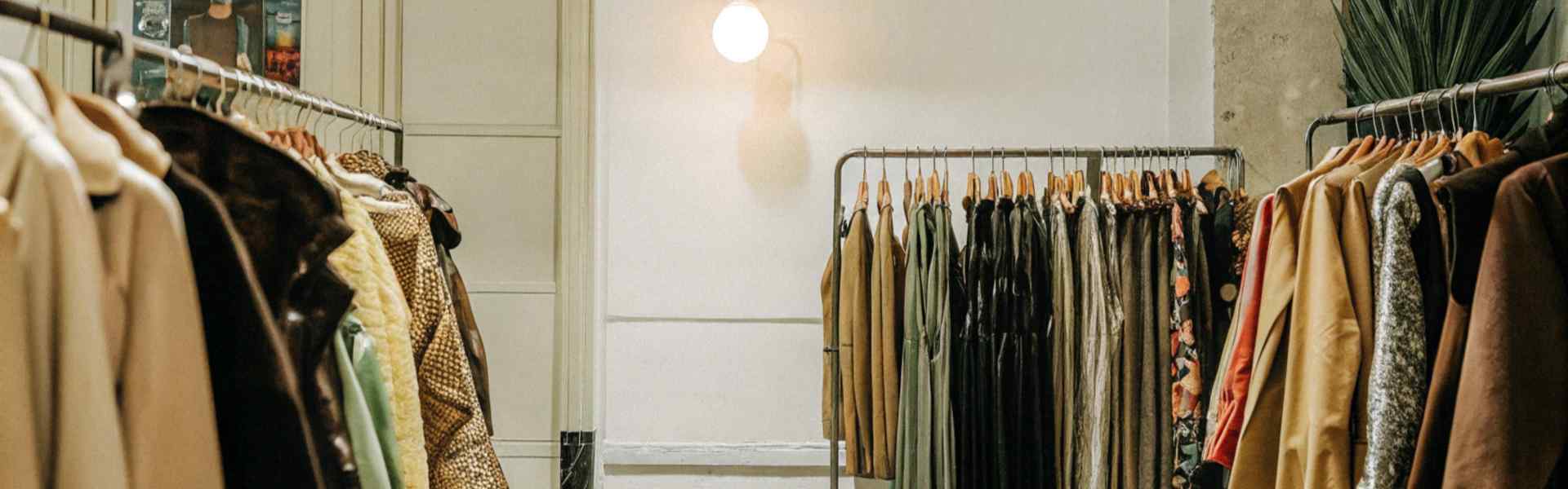 A clothing boutique showcasing coats and dresses under soft lighting with wall decor.