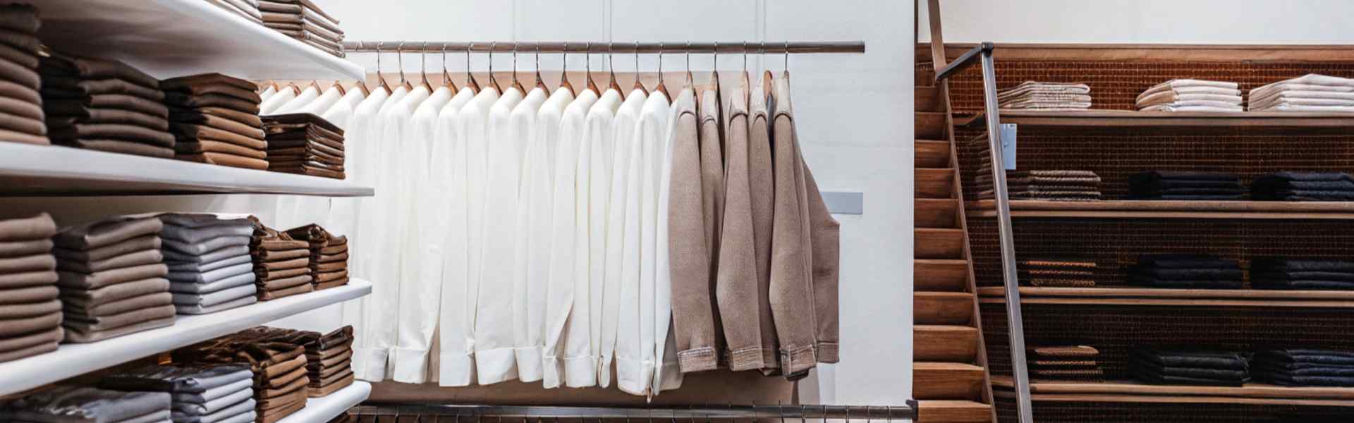 Shelves and racks displaying neatly folded shirts and pants in a brightly lit clothing store.