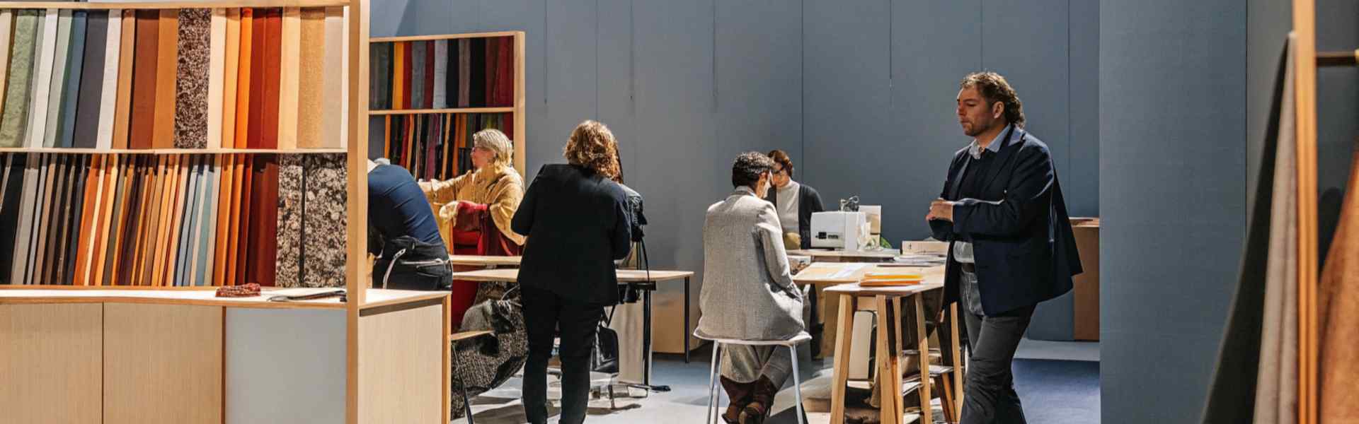 People working in a fabric design studio surrounded by colorful material samples.