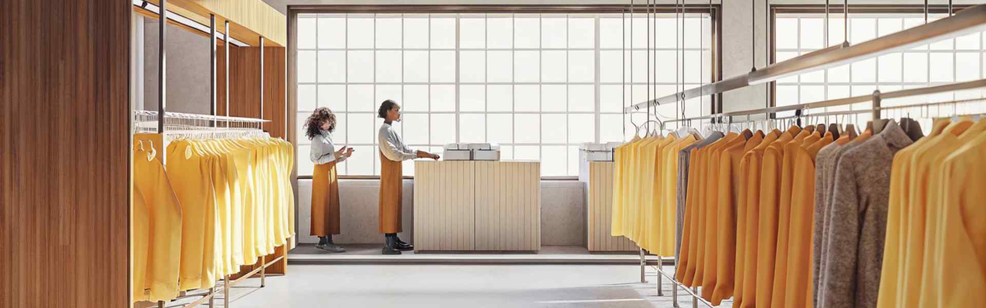 A clean, well-lit boutique with yellow garments displayed on racks and two employees at a counter.