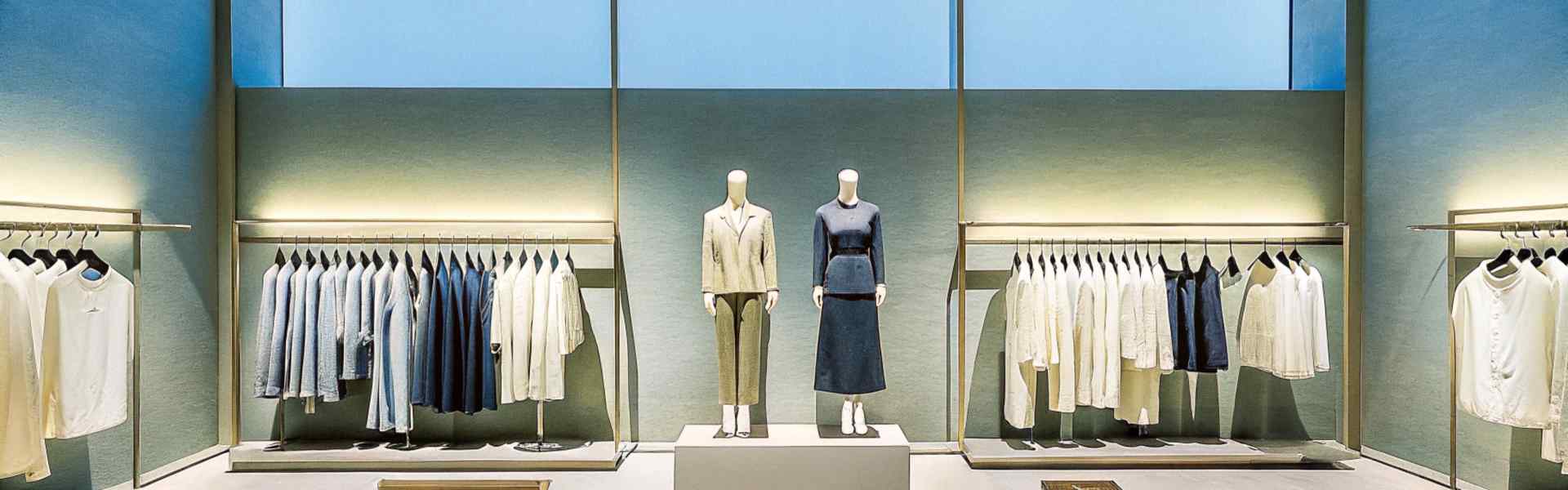 Elegant retail display with mannequins and racks of clothing under a skylight.