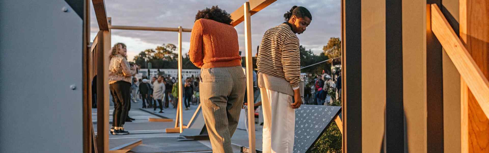 People exploring an outdoor installation during a lively event at sunset.