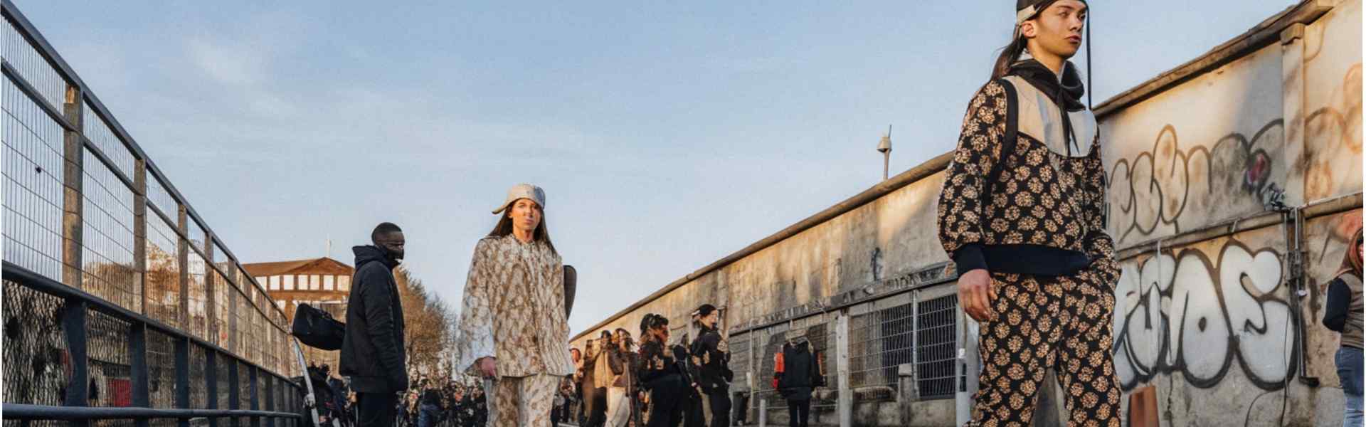 Models walking on a city street in stylish patterned outfits during a streetwear fashion event.