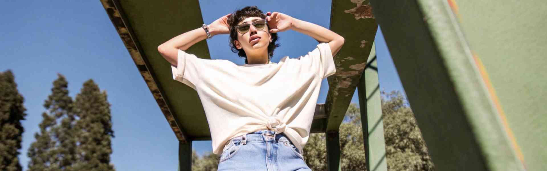 A stylish woman wearing a graphic t-shirt and ripped jeans outdoors.