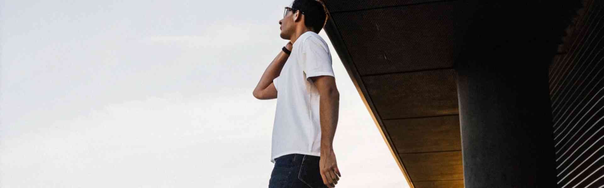 Man wearing dark jeans and white sneakers walking at sunset.