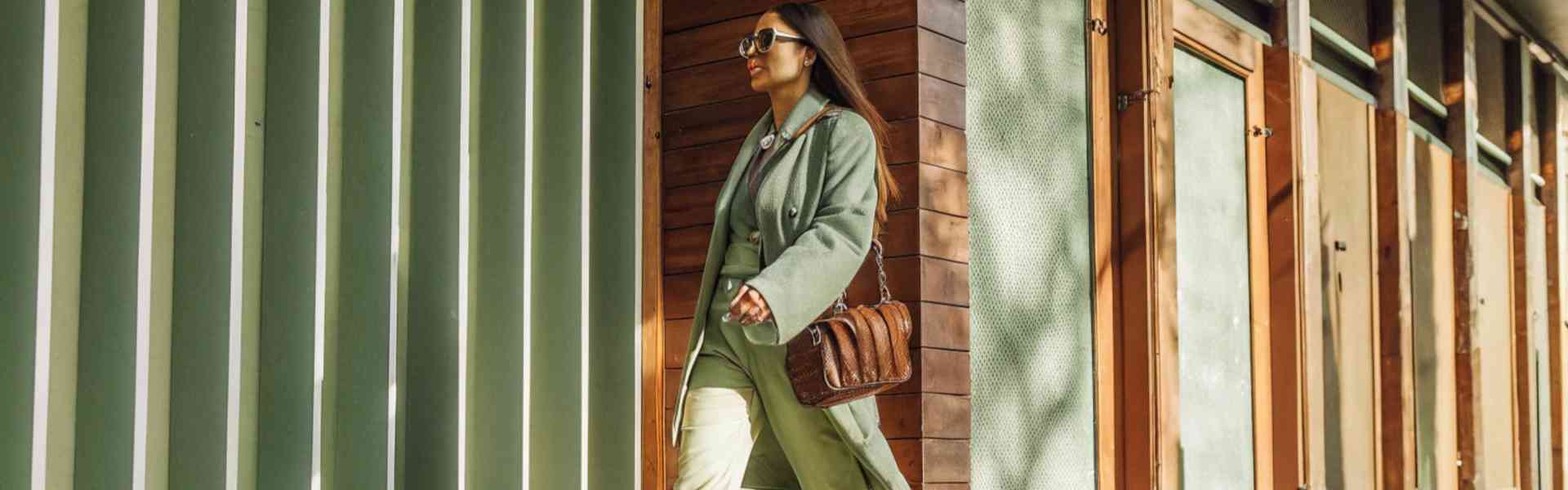 A stylish woman in a green outfit walking confidently down the street.