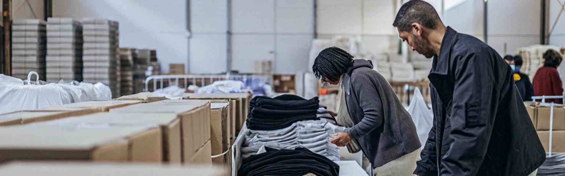 Workers sorting folded clothes in a warehouse.