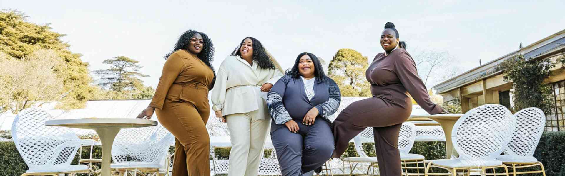 Four fashionable women posing outdoors in coordinated outfits.