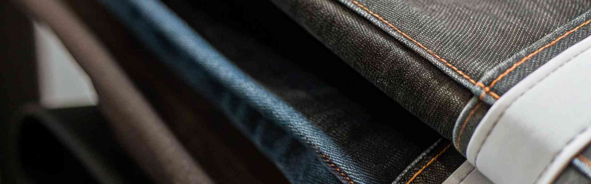 A stack of folded denim jeans in various colors and textures.