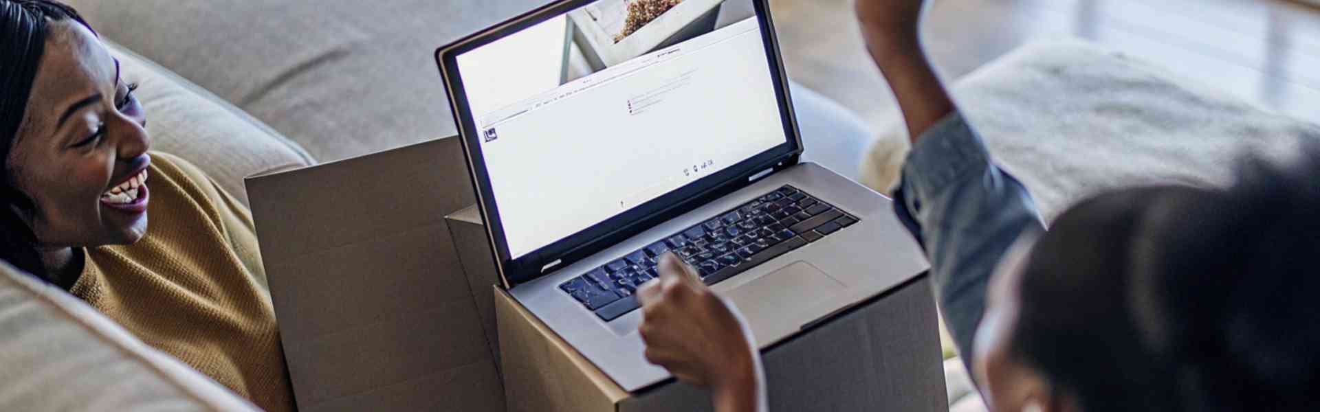 Two women celebrating while shopping online on a laptop.