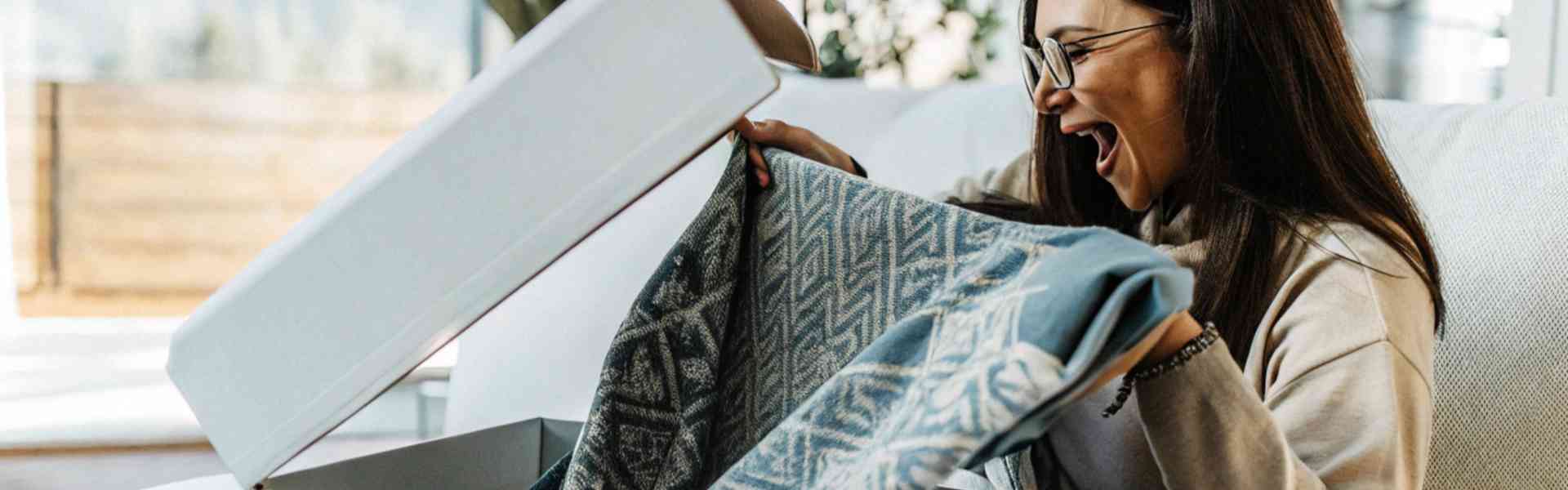 A woman excitedly opening a package and admiring a patterned fabric.