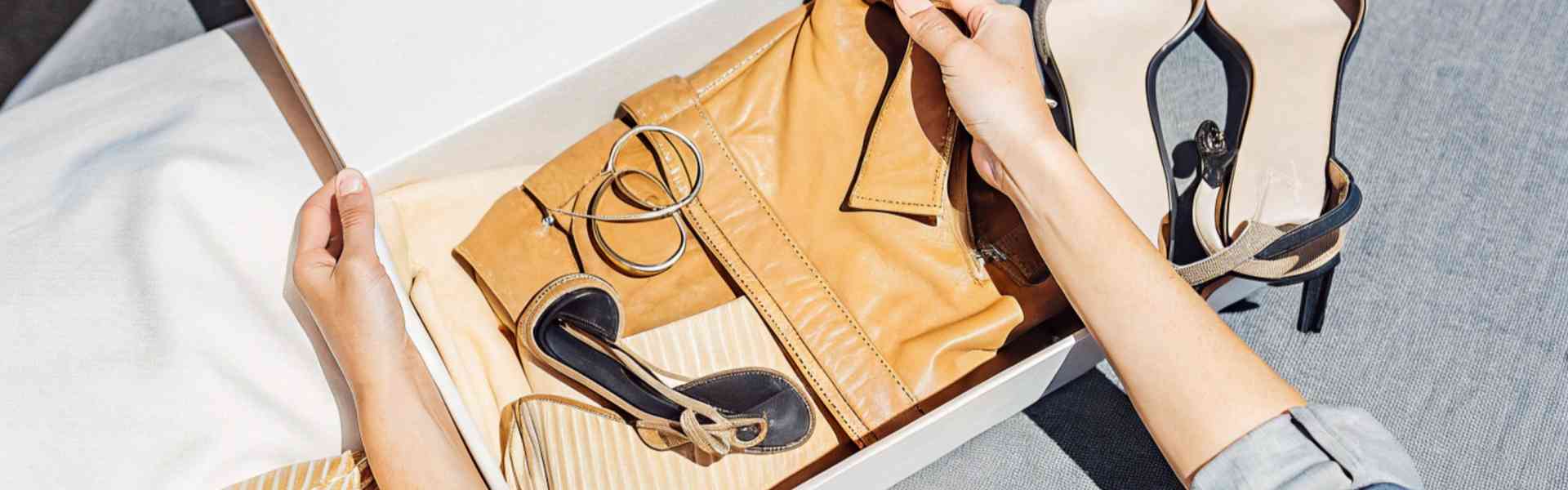 A person unboxing stylish clothing and accessories.