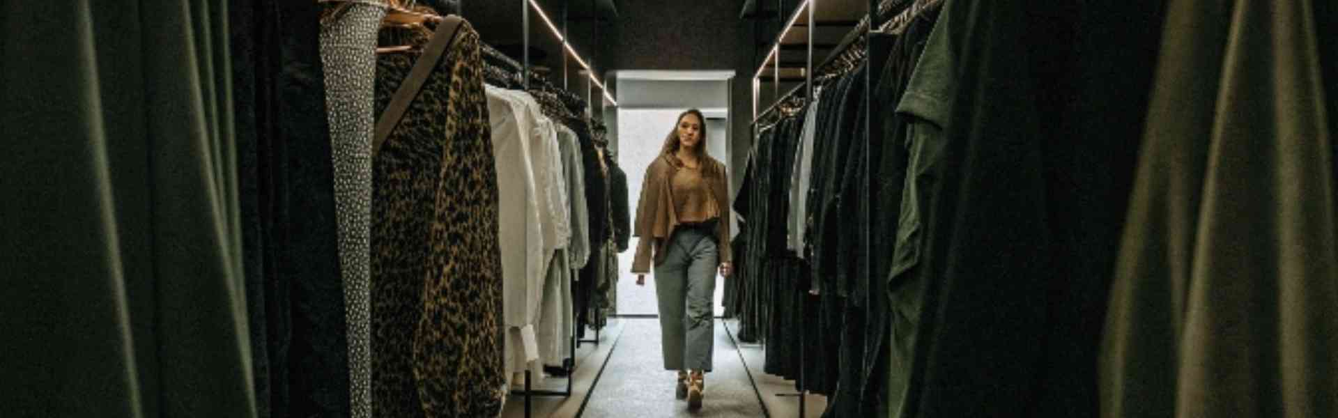 A stylish woman walks through a high-end boutique with elegant clothing displays.