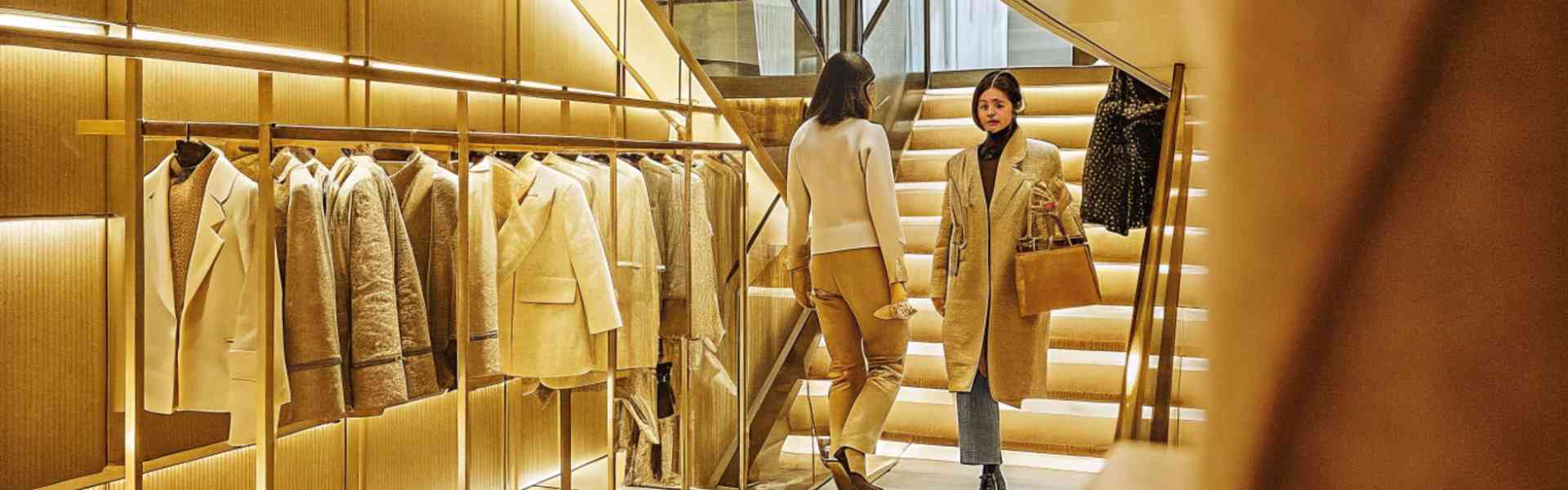 Elegant women shopping in a high-end boutique with golden lighting.