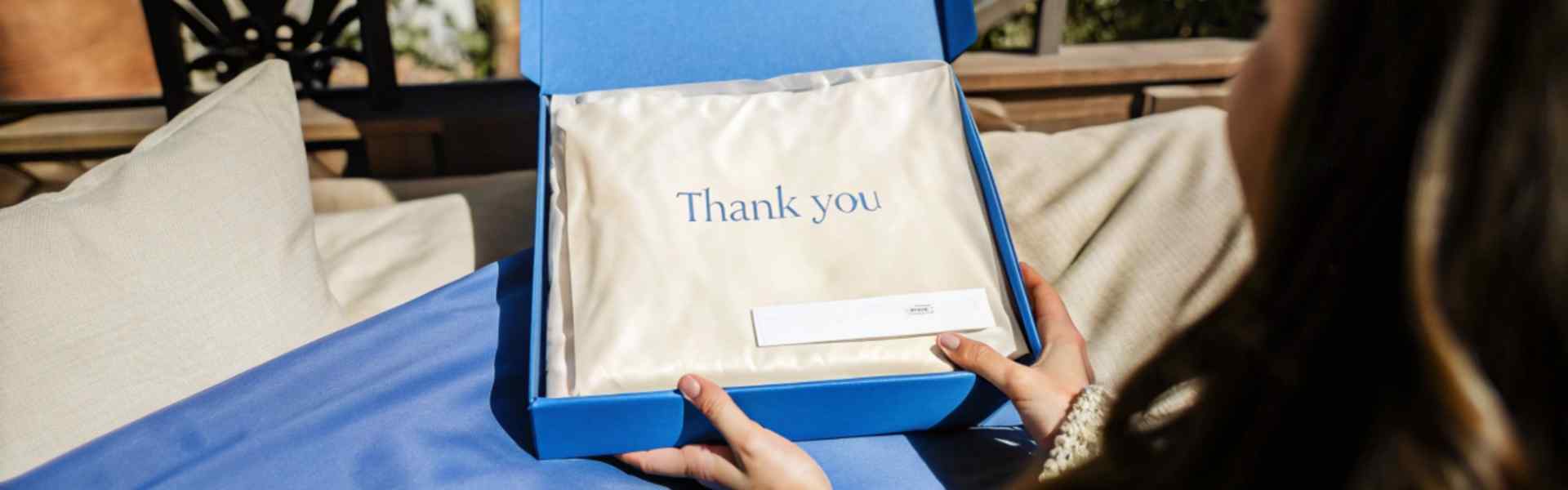 Woman unboxing a thank-you package in a blue box.