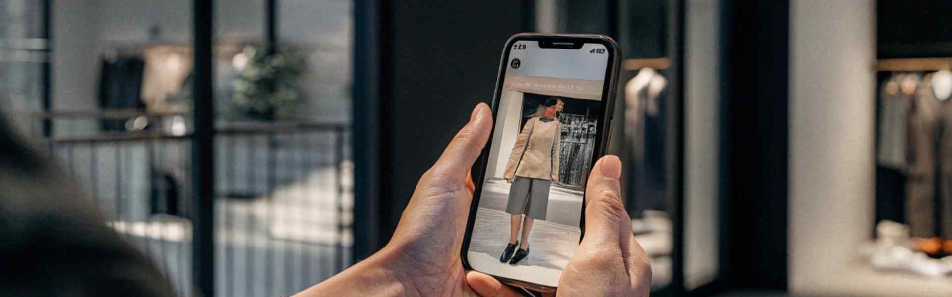 Person browsing a fashion website on a smartphone inside a clothing store.