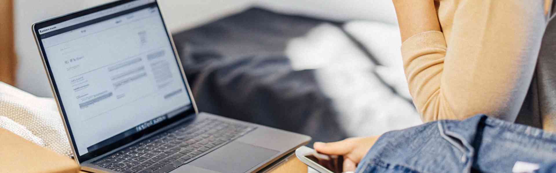 A woman checking her laptop while shopping online with packages nearby.