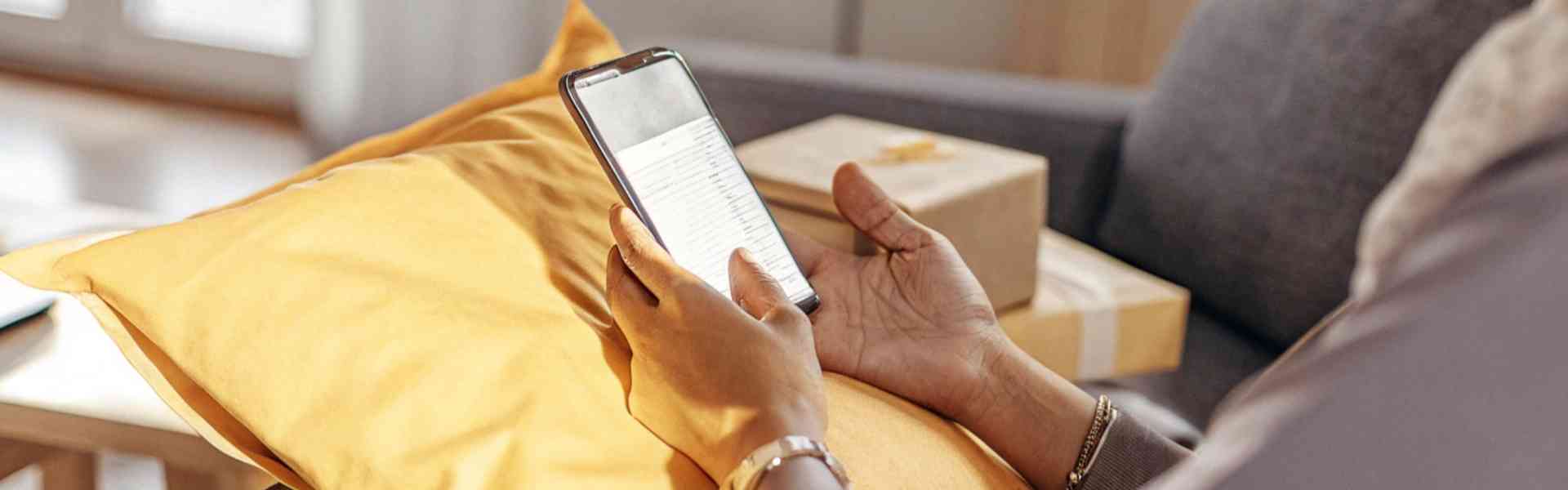 Woman browsing on her phone with packages beside her.