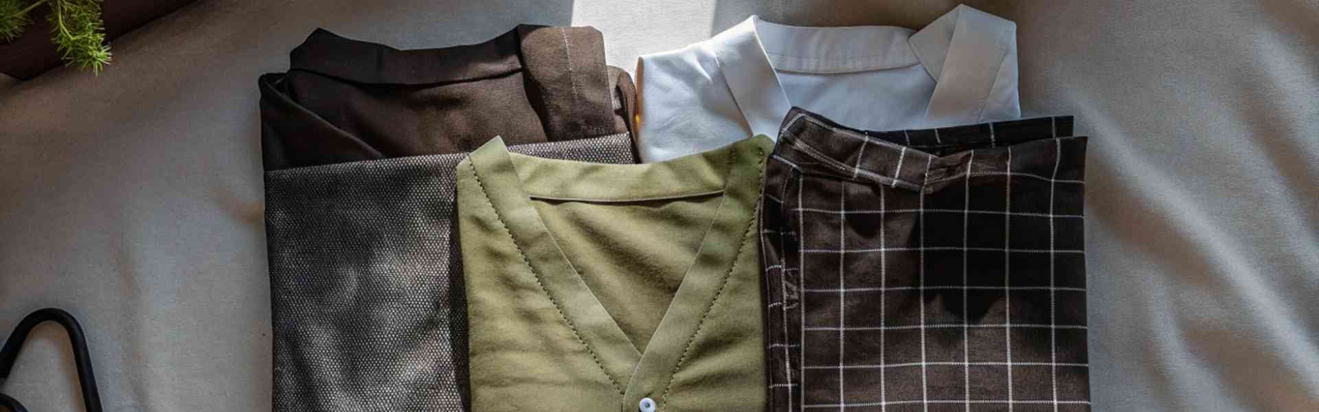 Neatly folded clothes in earthy tones on a fabric surface.