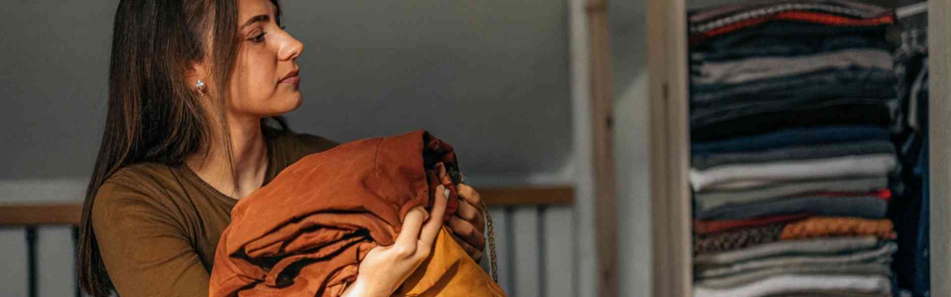 A woman sorting through clothes and placing them in a box.