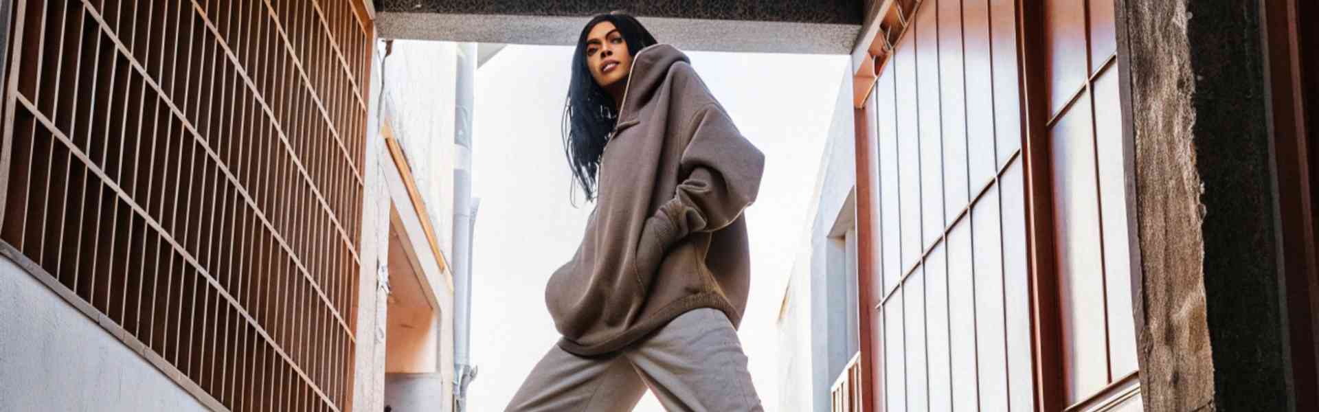 Woman in an oversized hoodie and sweatpants posing confidently.