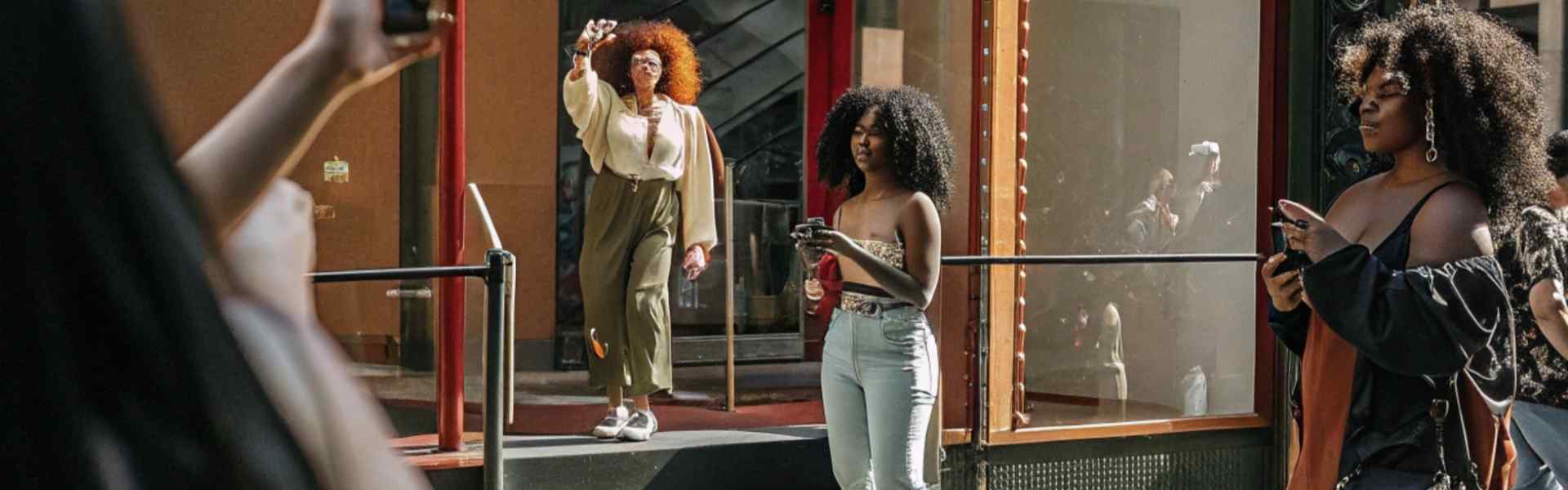 Stylish women taking photos outside a fashion store.