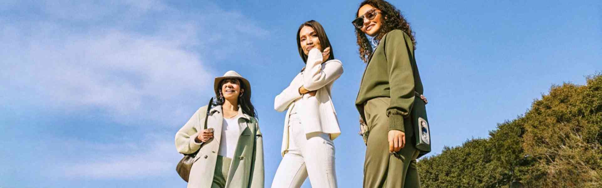 Three stylish women in coordinated outfits walking confidently outdoors.