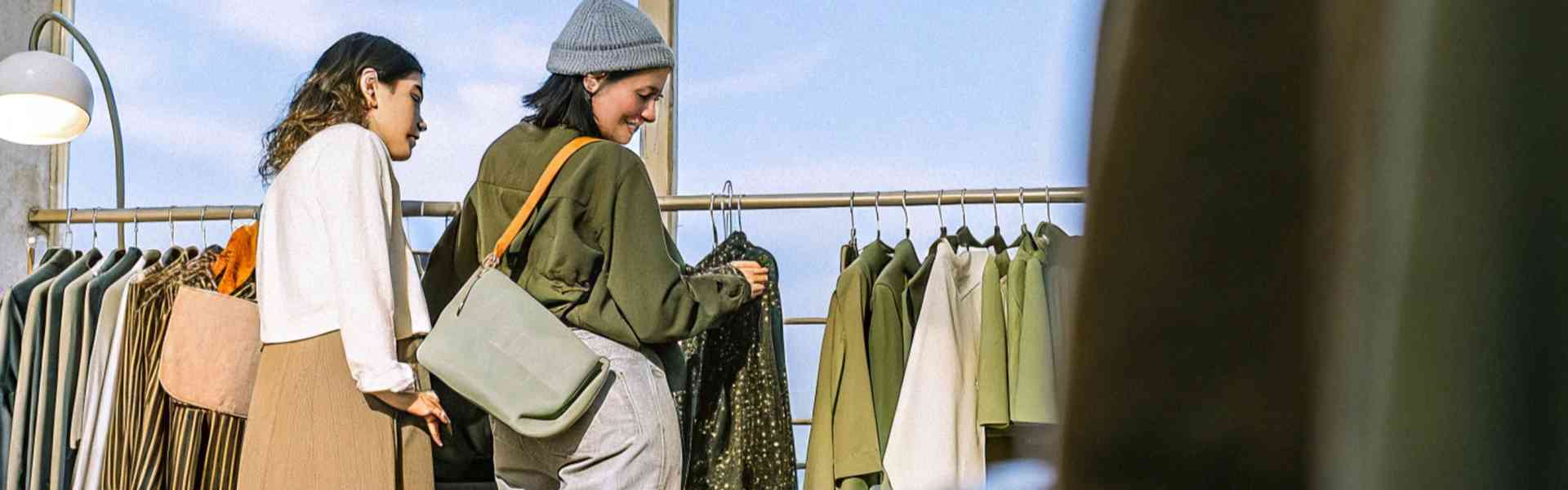 Two women shopping for clothes in a boutique with a bright sky view.