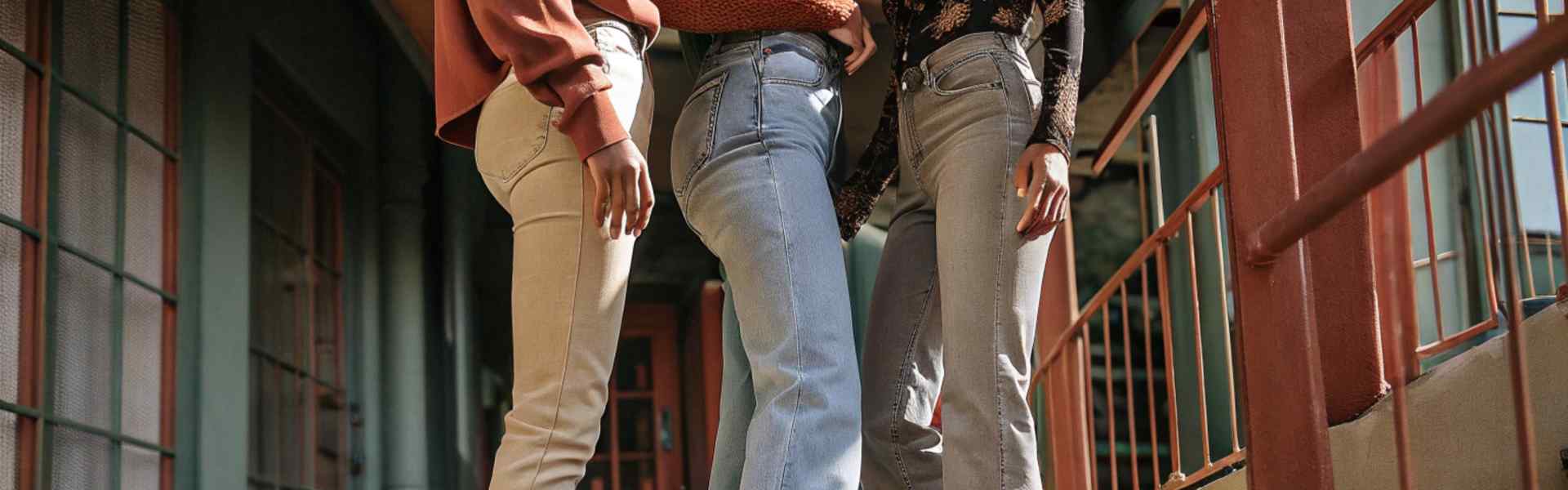 Three women wearing stylish denim jeans outdoors.