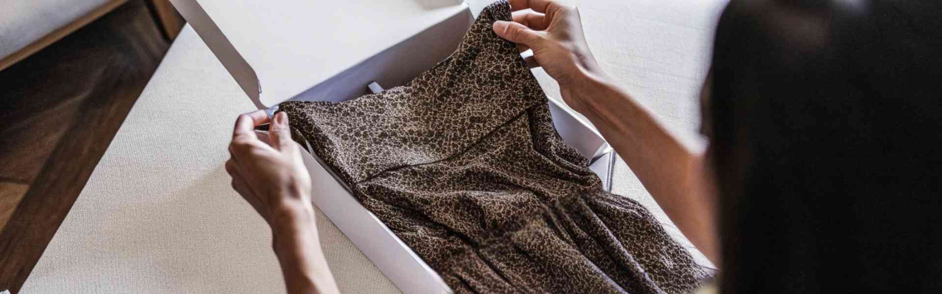 Woman opening a box with a leopard print dress inside.