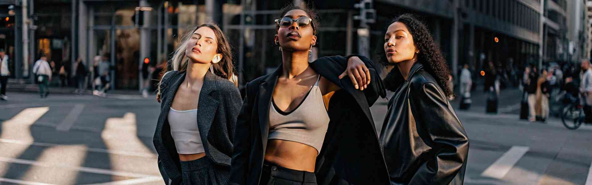 Three stylish women in black outfits walking confidently in the city.