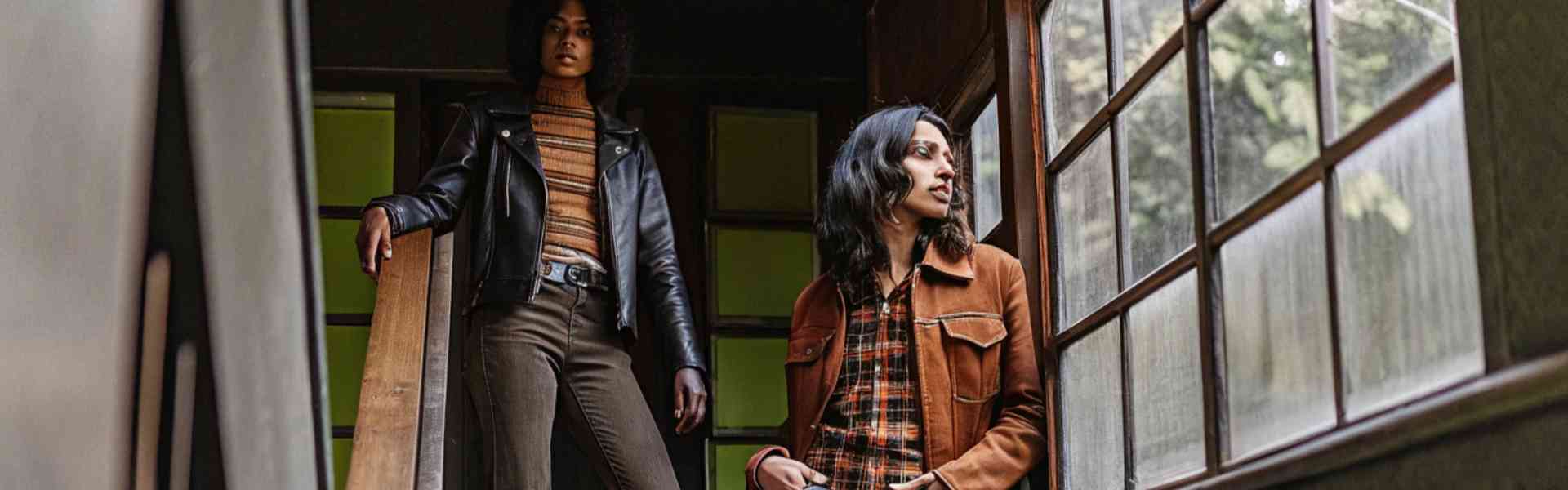 Two women wearing retro-style denim outfits on a staircase.