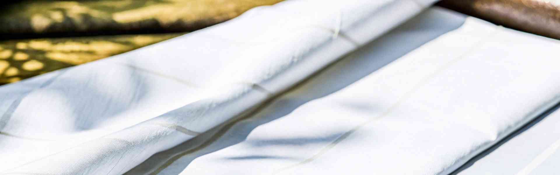 Soft white fabric with subtle stripes under natural light.