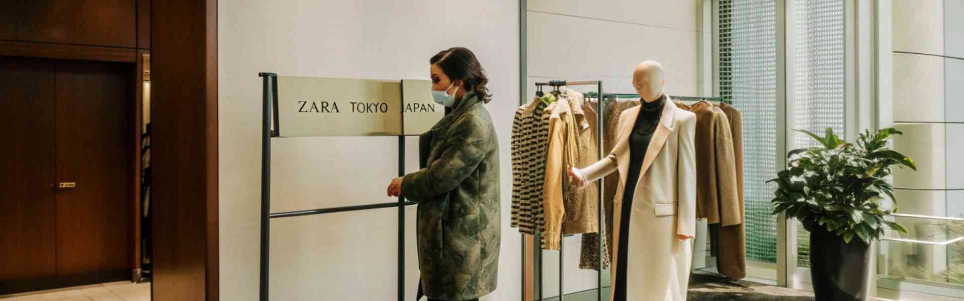 A woman wearing a mask browsing clothes at Zara Tokyo.