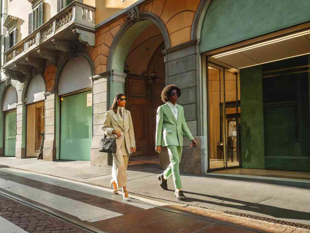 Two fashionable women walking down a European street in tailored suits.