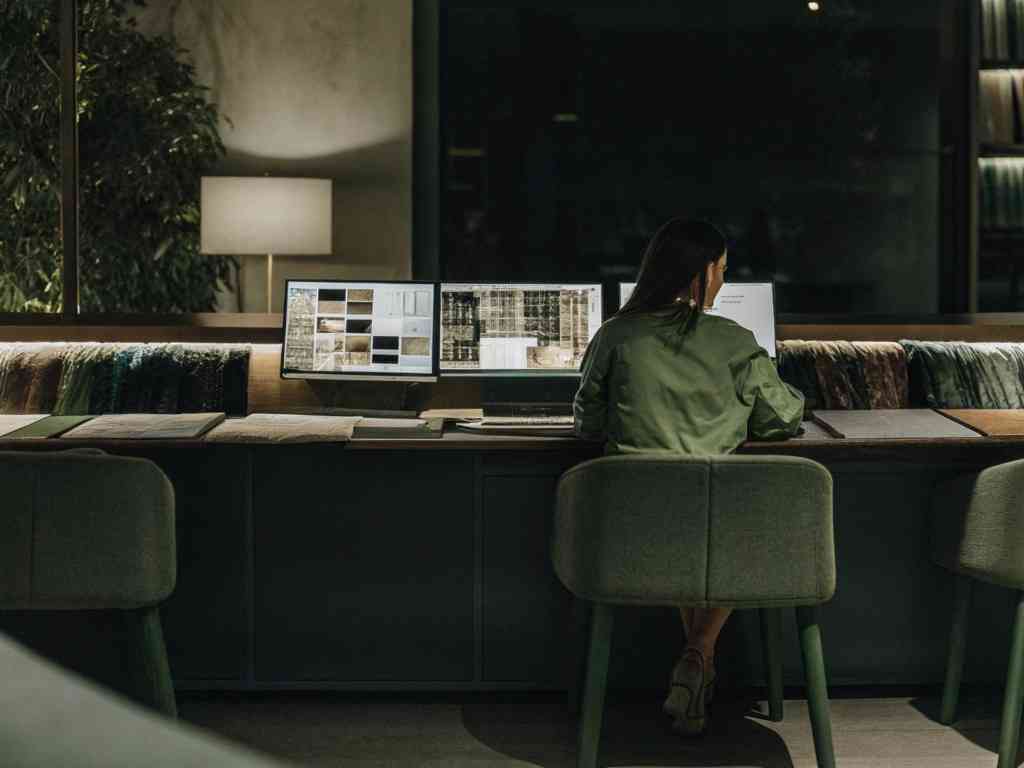 A woman working on fabric designs at a computer workstation.