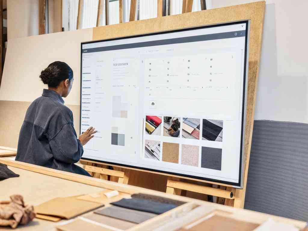 A designer working on a large touchscreen with fabric samples.