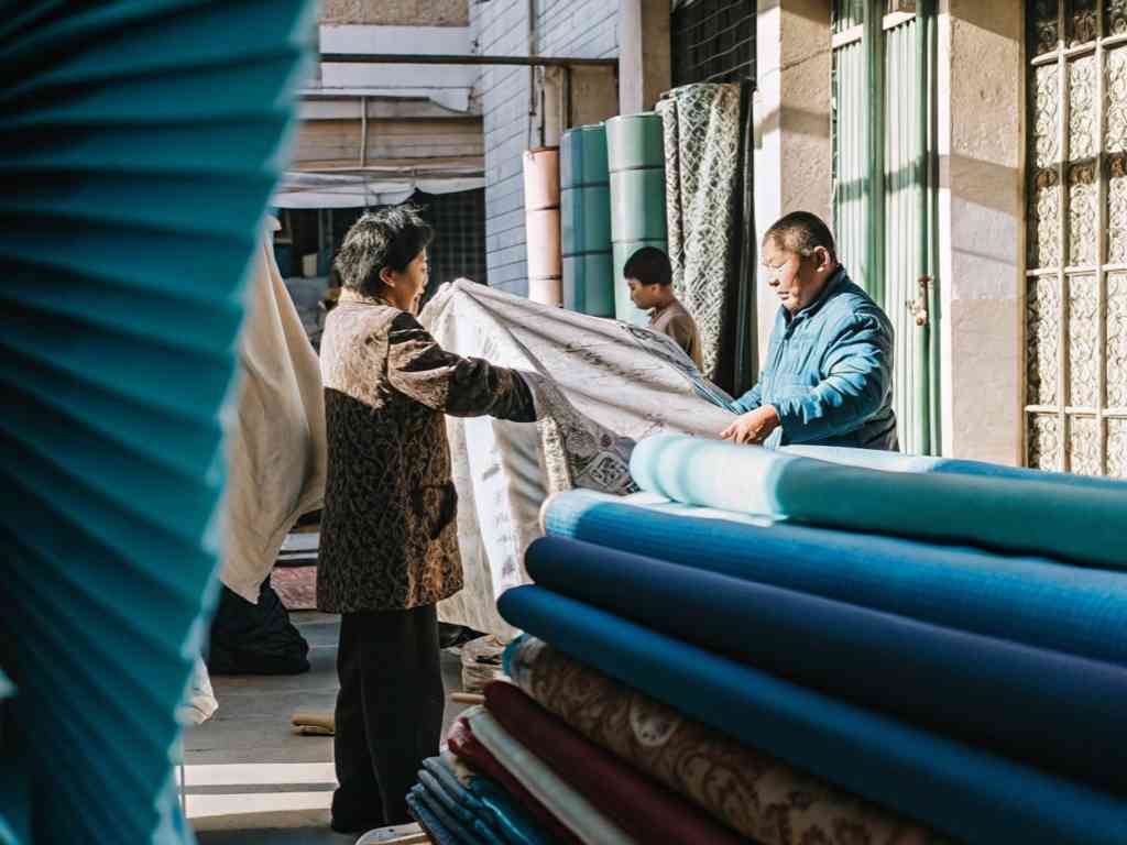 A woman and a vendor inspecting fabric at an outdoor textile market.