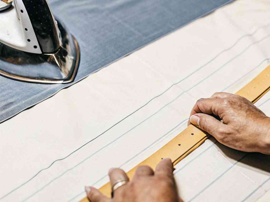 Hands aligning belt on striped fabric.