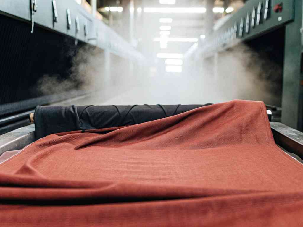 Red fabric being steamed in textile processing machine.